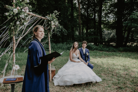 Charlotte Waardenburg spreekt en een bruidspaar kijkt toe