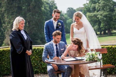 Trouwambtenaar Ingrid Ebens staat naast een bruidspaar en getuigen